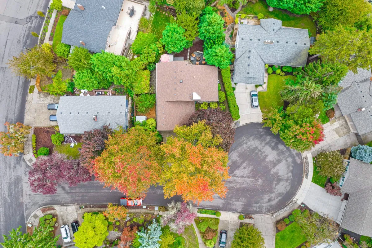 An inviting view of a peaceful neighborhood with leafy tree canopies and well-maintained homes and gardens. The scene suggests pleasant streets perfect for family strolls, proximity to parks, and a serene atmosphere ideal for outdoor family adventures.