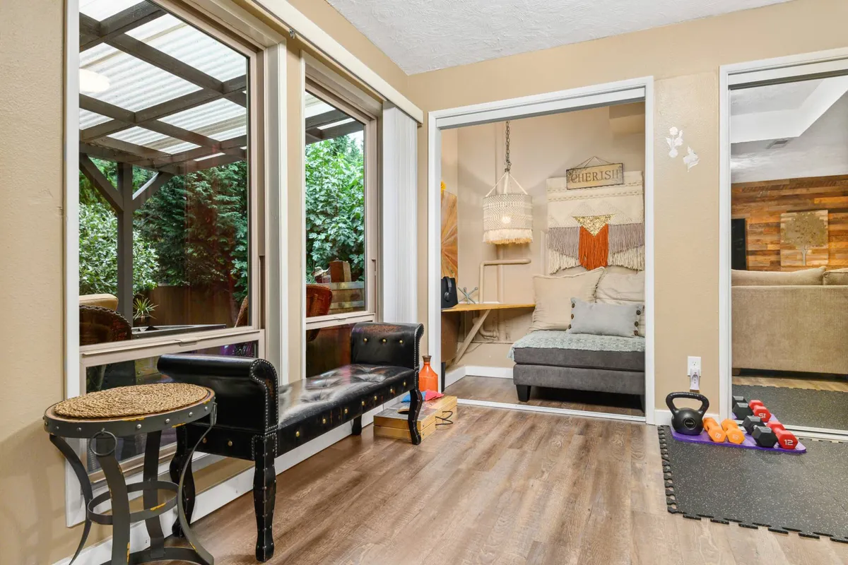 A welcoming seating area with large windows that showcase lush greenery outside. The comfortable chairs and decorative wall create a cozy nook flooded with natural light, hinting at the connection between indoor relaxation and the outdoors.